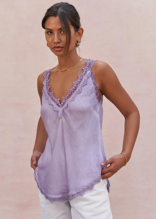 Woman wearing a light purple lace-trimmed top against a beige background