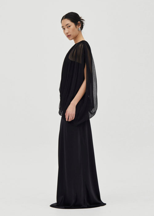 Woman wearing a black dress with sheer sleeves on a white background