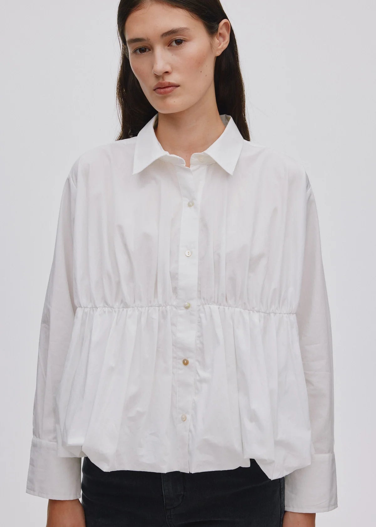 Woman wearing a white button-up shirt on a plain background
