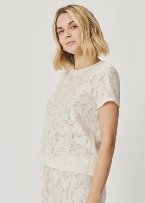 Woman wearing a white t-shirt with a subtle pattern on a plain background