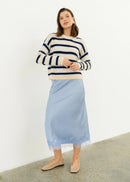 Woman wearing a striped sweater and light blue skirt on a white background