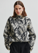 Woman wearing a patterned sweater on a plain background