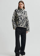 Woman wearing a patterned sweater on a plain background
