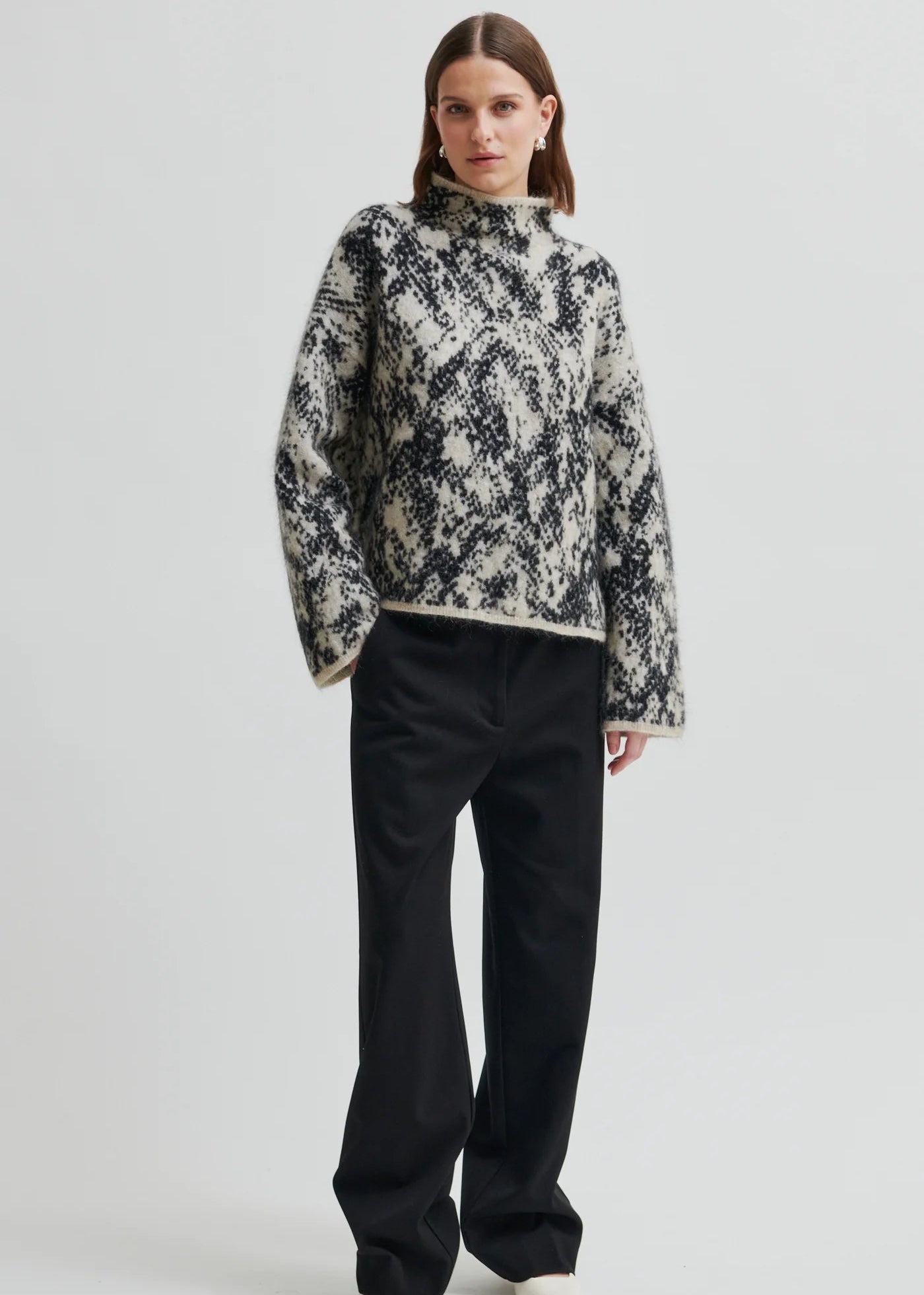 Woman wearing a patterned sweater on a plain background
