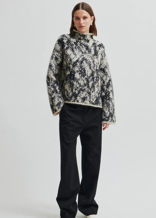 Woman wearing a patterned sweater on a plain background