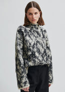Woman wearing a patterned sweater on a plain background