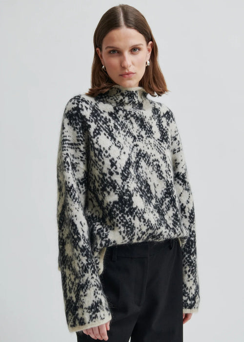Woman wearing a patterned sweater on a plain background