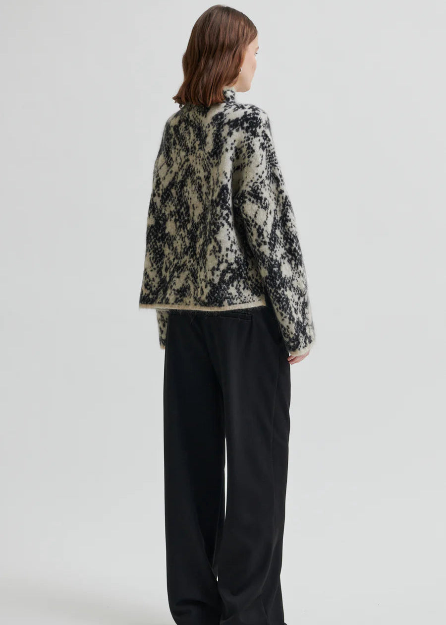 Woman wearing a patterned sweater on a plain background