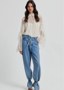 Woman wearing a lace blouse and blue jeans on a white background