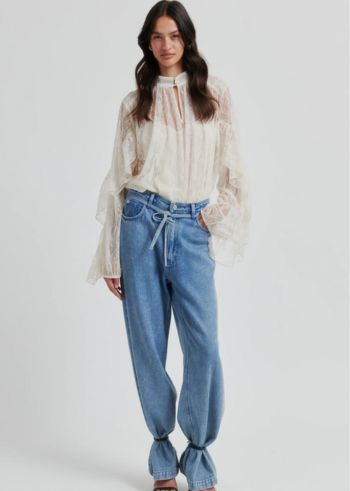 Woman wearing a lace blouse and blue jeans on a white background