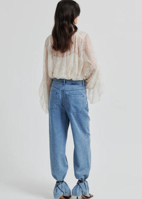 Woman wearing a lace blouse and blue jeans on a white background