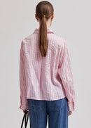 Woman wearing a pink  shirt with blue jeans on a light grey background