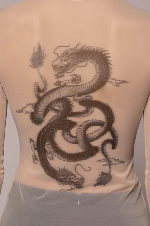 Woman wearing sheer top with dragon image on light background