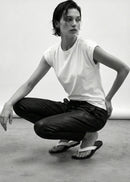 Person in a white t-shirt and black pants posing in a studio setting