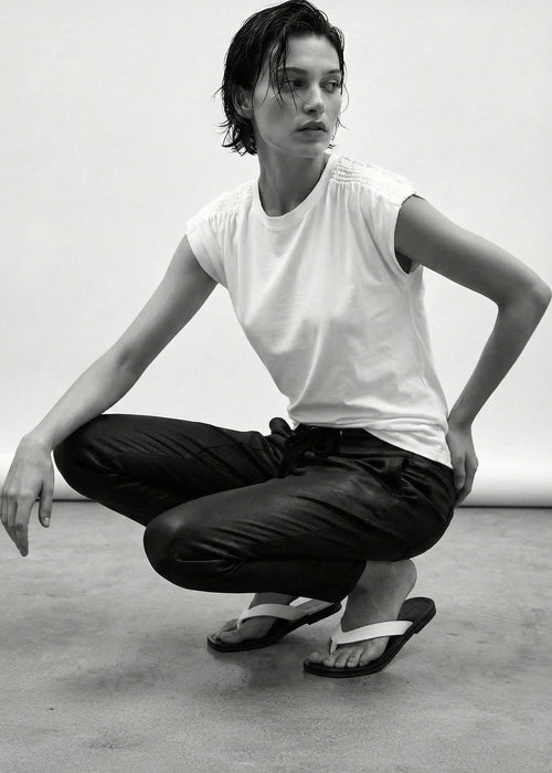 Person in a white t-shirt and black pants posing in a studio setting