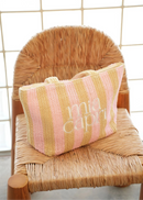 Striped bag with 'mia capri' branding on a wicker chair against a tiled wall.
