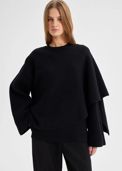 Woman wearing a black oversized wrap top on a white background