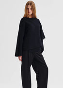 Woman wearing a black oversized wrap top on a white background