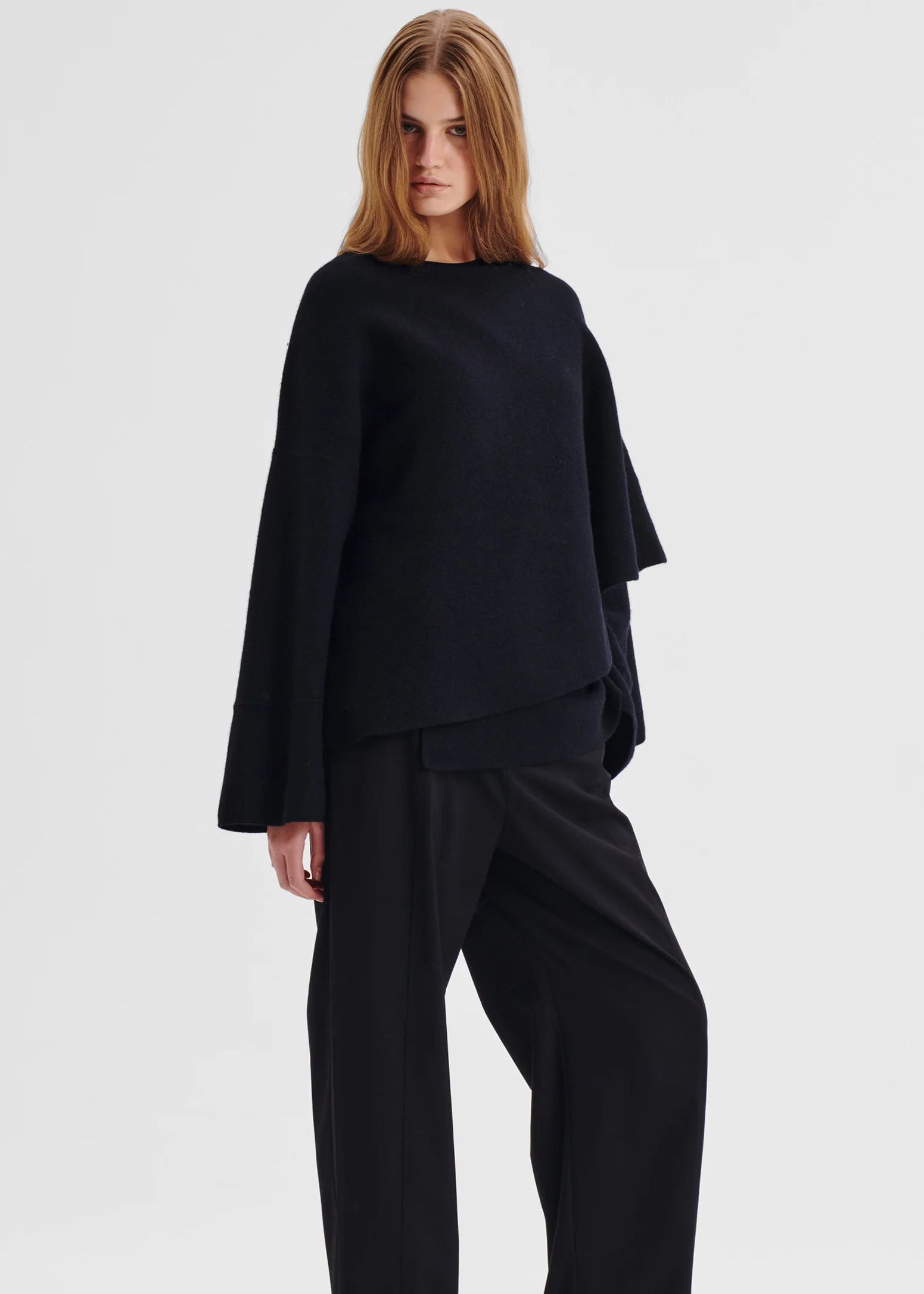 Woman wearing a black oversized wrap top on a white background
