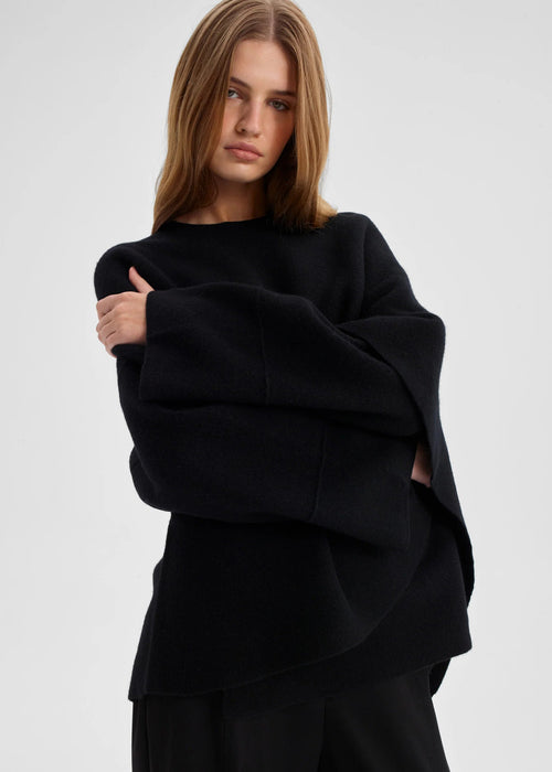 Woman wearing a black oversized wrap top on a white background