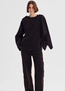 Person wearing a dark purple poncho against a white background