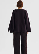 Person wearing a dark purple poncho against a white background
