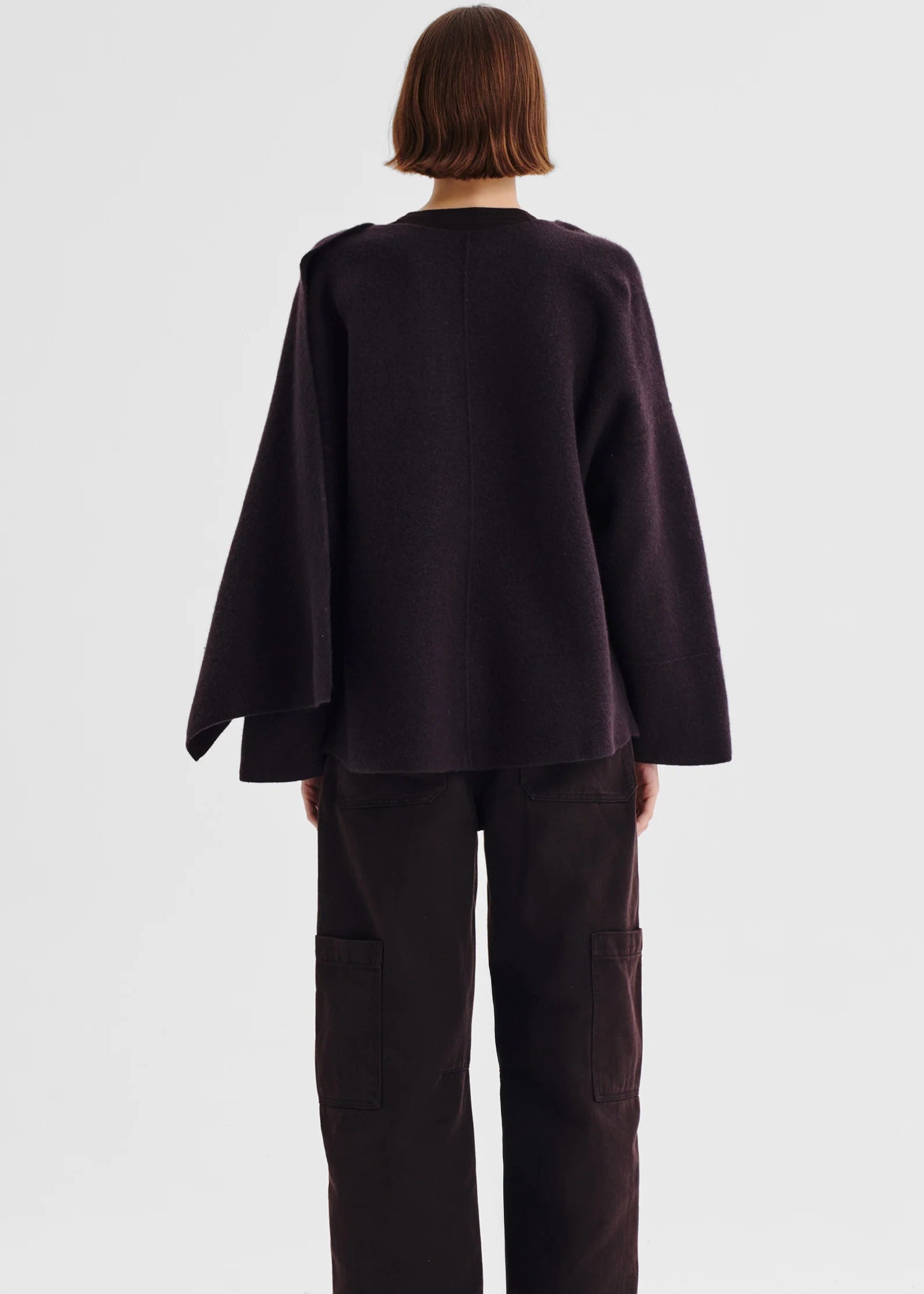 Person wearing a dark purple poncho against a white background