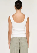A woman viewed from the back wearing a white sleeveless top and wide-leg striped pants in a light sage green and white colourway, set against a plain off-white studio background.