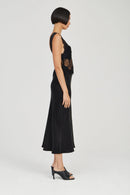 Woman wearing a black sleeveless dress with floral embroidery on a white background