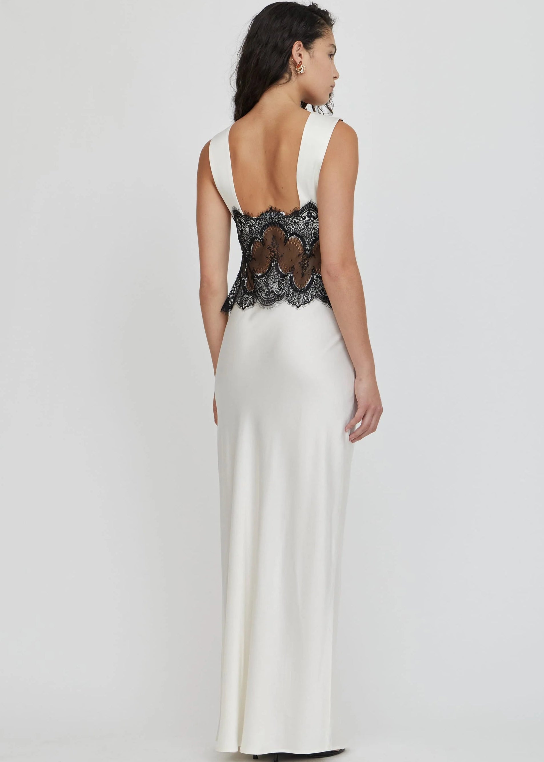 Woman wearing a black lace top and white skirt on a white background