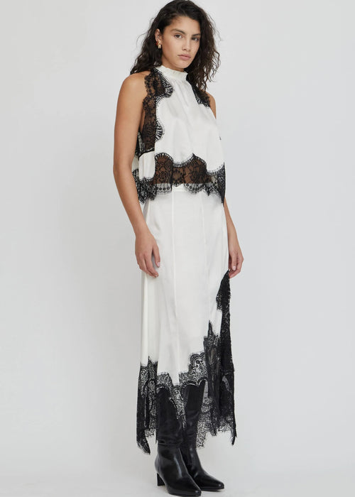 Woman wearing a white dress with black lace details on a white background