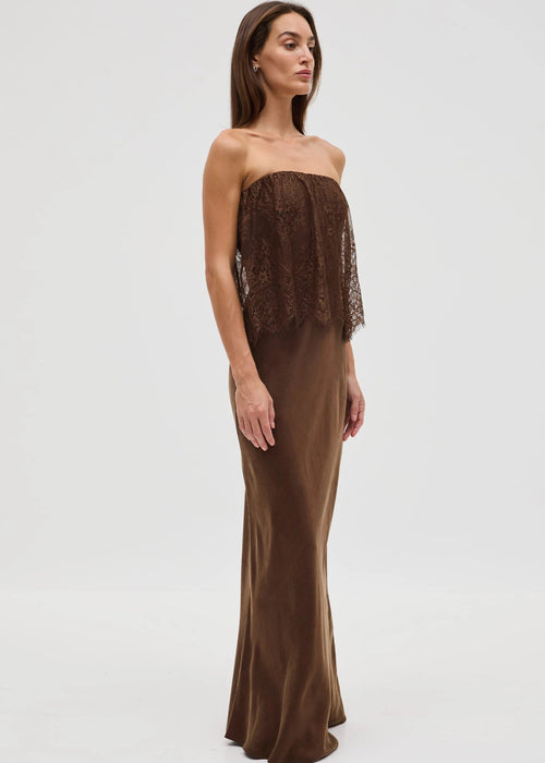 Woman wearing a brown strapless dress with lace detailing on a white background