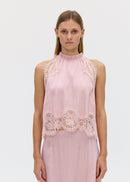 Woman wearing a pink lace top on a white background