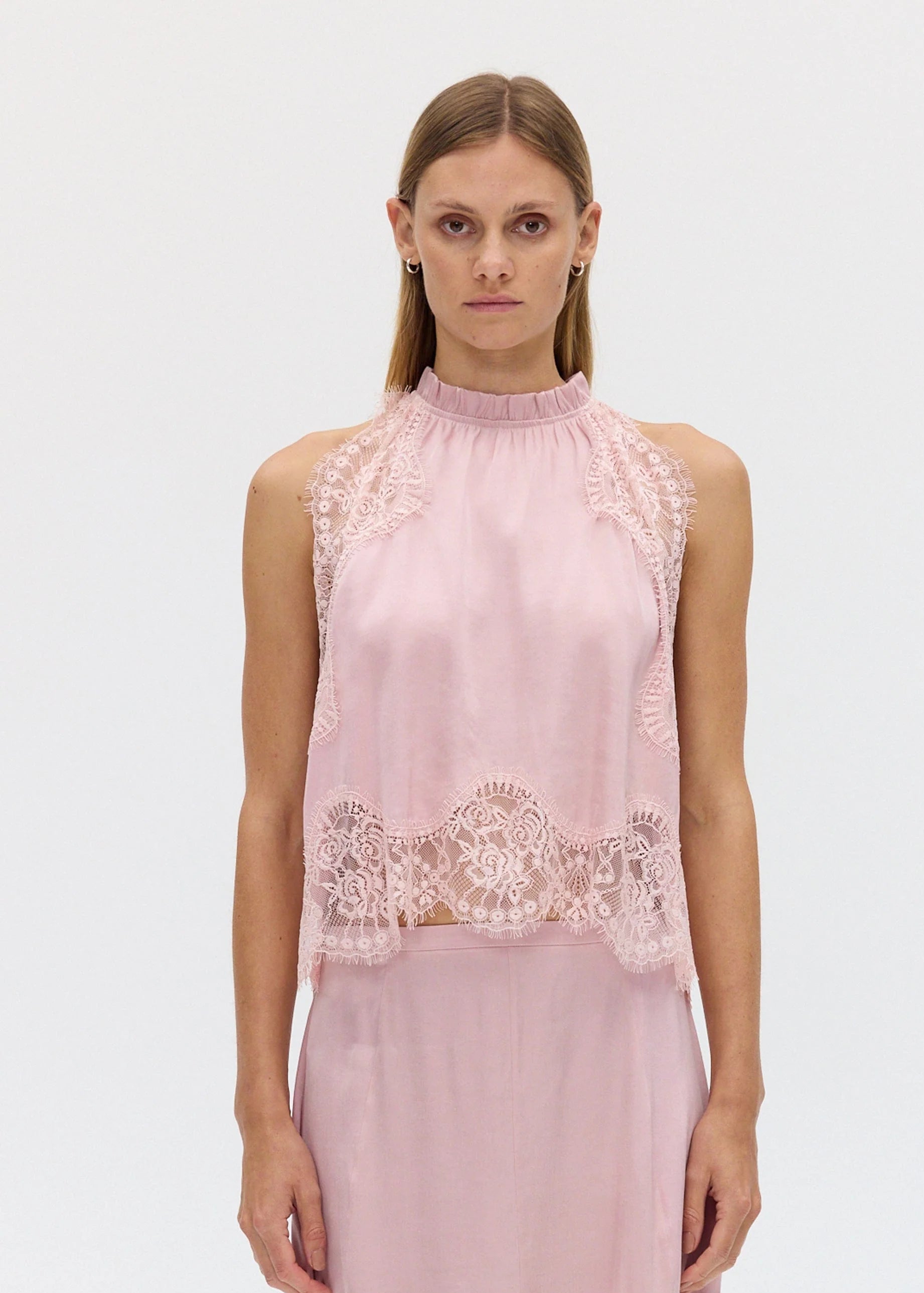 Woman wearing a pink lace top on a white background