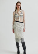 Model wearing a sheer blouse with floral embroidery against a white background