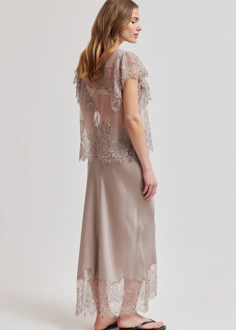 Woman wearing a lace top and skirt with a plain background