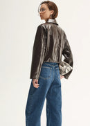 Person wearing a shiny brown jacket and blue jeans on a white background