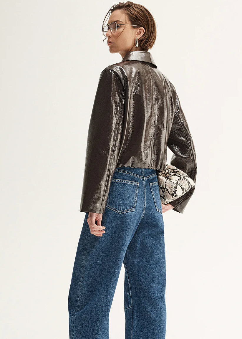 Person wearing a shiny brown jacket and blue jeans on a white background